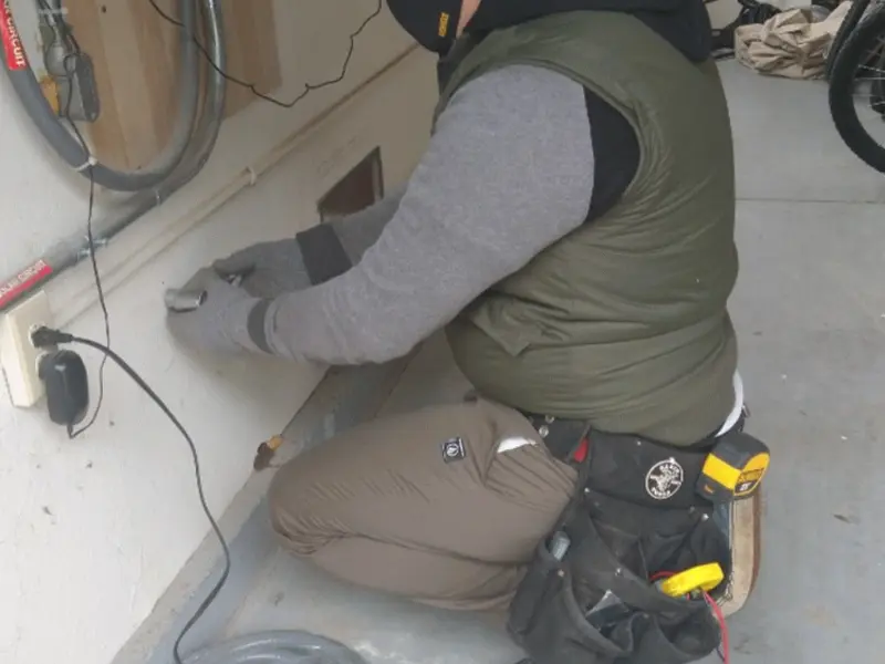 Electrician performing outlet wiring in a Dedham garage